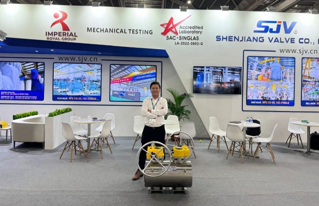 Imperial Royal team member at the joint Imperial Royal and Shenjiang Valve exhibition booth with a large actuated ball valve